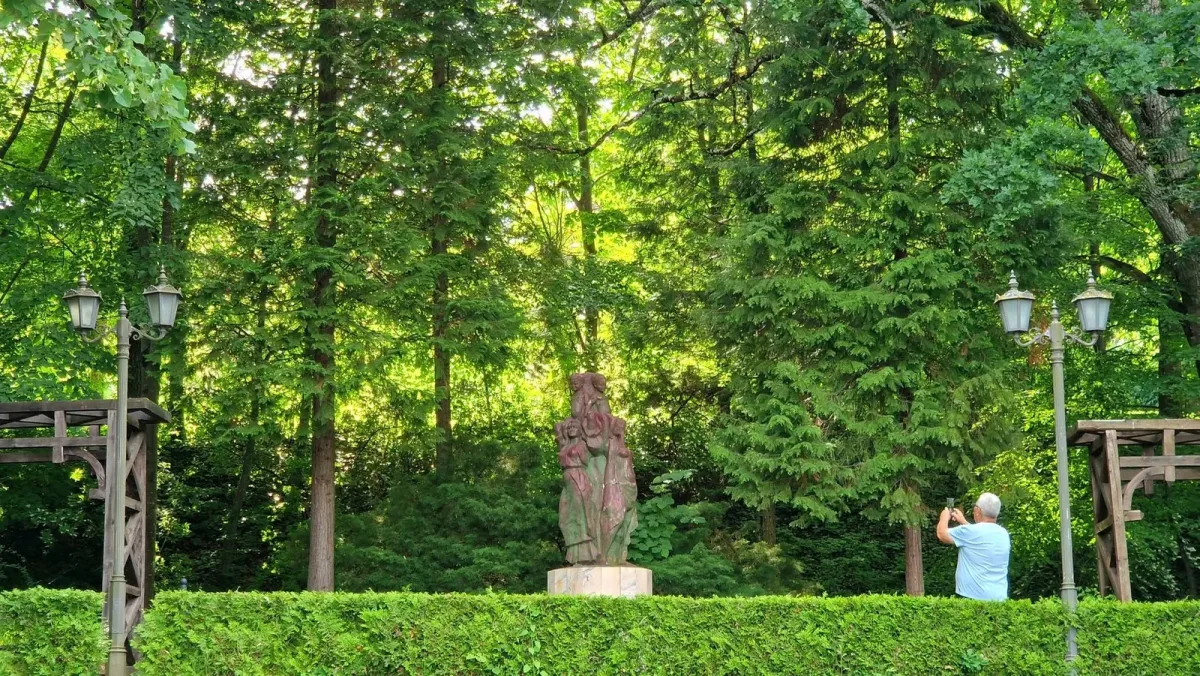 Statuie încadrată de arbori și alei în parcul Băile Govora.